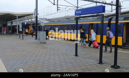 Passagiere, die auf einem Bahnsteig am Bahnhof Venlo in den Niederlanden spazieren gehen. Stockfoto