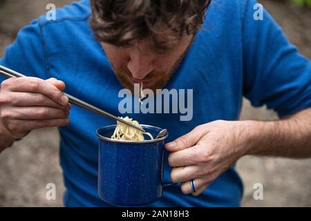 Ein Mann, der Camping-Ramen isst. Stockfoto