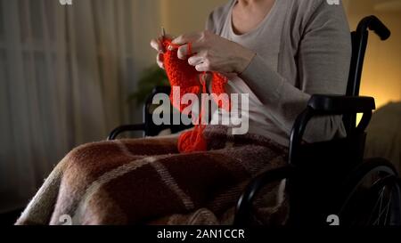 Seniorin sitzt im Rollstuhl und strickt, genussvolles Hobby, Nahaufnahme Stockfoto