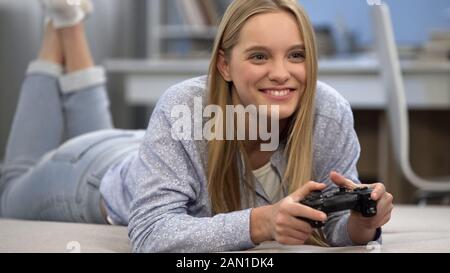 Aufgeregte Dame spielt leidenschaftlich Videospiel mit Joystick, professioneller Gamer Stockfoto