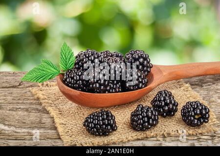 Blackberry im Löffel auf dem alten Holztisch mit unscharfen Garten Hintergrund Stockfoto