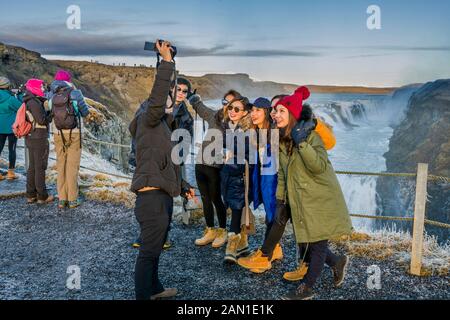 Touristen aus Asien fotografieren bei den Wasserfällen von Gullfoss, Island Stockfoto