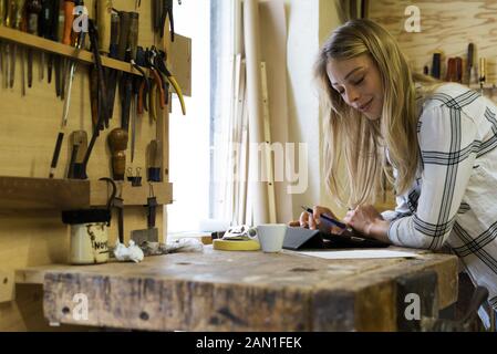 Frau mit digitalen Tablet in Werkstatt Stockfoto