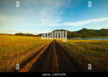 Schuttweg durch grasbewachsene Landschaft Stockfoto