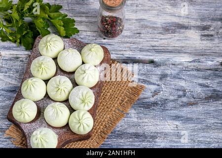 Gefrorener Teig khinkali mit Spinat. Garniert mit Red Chili, Dill und Petersilie. Auf Holzgrund. Kopierbereich. Stockfoto