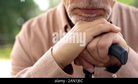 Männliche Rentner in Garten, Hände und Kinn auf Gehstock closeup, Alterung Problem Stockfoto