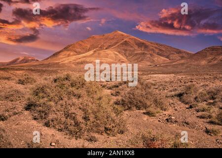 Blick auf die vulkanischen Berge Hacha Grande in der Nähe von einem Strand in Lanzarote, Spanien bei Sonnenuntergang Stockfoto