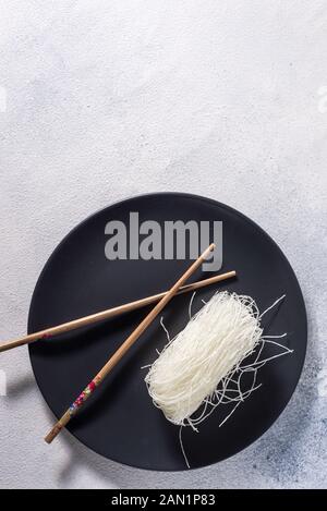 Chinesische Glasnudeln mit Stäbchen auf einem dunklen Platte mit Platz für Text Stockfoto