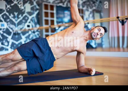 Ein Mann, der eine Seitenwand macht, während er in einem Fitnessstudio arbeitet. Stockfoto