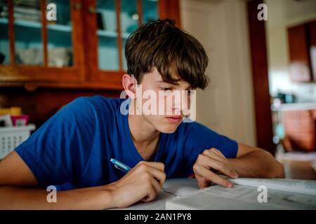 15 Jahre alter Junge mit Cochlea Implantat zu Hause studieren Stockfoto