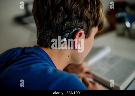 Rückansicht des Teenage Jungen mit Cochlea Implantat Hausaufgaben zu tun Stockfoto
