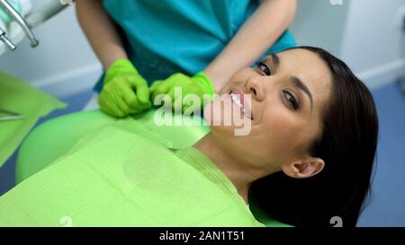 Glückliche Frau an der Kamera lächelnd in der zahnmedizinischen Klinik, zufriedener Kunde nach dem Check-up Stockfoto