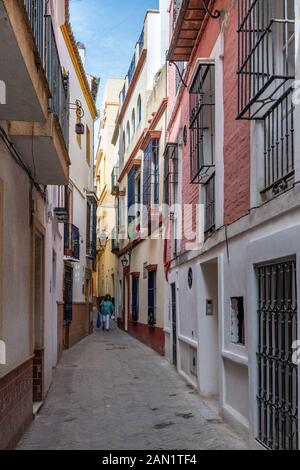 Bunte Gebäude umgrenzen eine enge Gasse im historischen jüdischen Viertel von Sevilla. Stockfoto