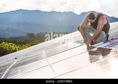 Arbeiter installiert Solarpaneele auf dem Dach des Gebäudes. Stockfoto