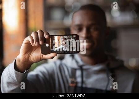 Positiver schwarzer Kellner macht selfie auf Handy im Restaurant Stockfoto