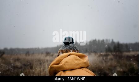 Die Rückseite eines Bommel Hut auf einem Kind spielen draußen im Schnee Stockfoto