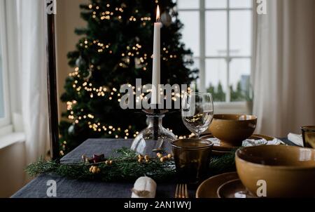 An Weihnachten eine Kerze auf einem festlich dekorierten Esstisch entzünden Stockfoto