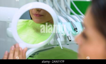 Nette Dame Lippen in reflektierenden Spiegel, Frau mit Behandlung von Zähnen zufrieden Stockfoto
