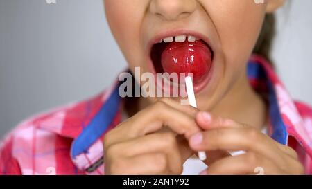 Süßes kleines Mädchen, die versuchen, Lollipop, Wirkung von Zucker auf die Zähne zu beißen, Zahnpflege Stockfoto