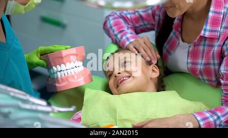 Pädiatrische Zahnarzt zeigen wenig lächelnde Mädchen künstliche Spannbacken, Bildung Stockfoto