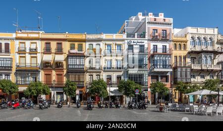 Bunte Gebäude (und geparkte Motorräder) führen an der östlichen Seite der Plaza de San Francisco in Sevilla. Stockfoto