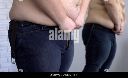 Übergewichtigen Mann, der versucht, Taste, um Jeans, Übergewicht, ungesunde Lebensweise Stockfoto