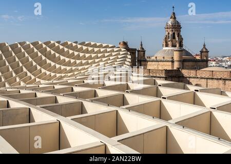 Die geschwungenen Linien von Jurgen Mayers Metropol-Parasol stehen im Kontrast zu der gekachelten Kuppel, der Kuppel und dem Glockenstuhl der Iglesia de la Anunciación aus dem 16. Jahrhundert. Stockfoto