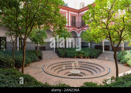 Ein Innenhof von Sevilla mit einem Springbrunnen und kreisförmigen, mit Fliesen verzierten Stufen bildet den Kreuzgang des Hospital de los Venerables. Stockfoto