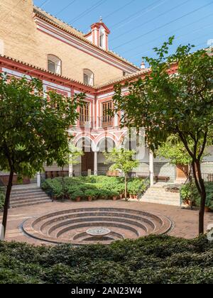 Ein Innenhof von Sevilla mit einem Springbrunnen und kreisförmigen, mit Fliesen verzierten Stufen bildet den Kreuzgang des Hospital de los Venerables. Stockfoto