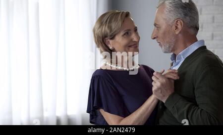 Alte Mann und Frau tanzen und zärtlich schauen einander an, glückliche Ehe Stockfoto