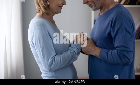 Älterer Mann, Frau, Hände, einander an und lächeln suchen, flirten Stockfoto