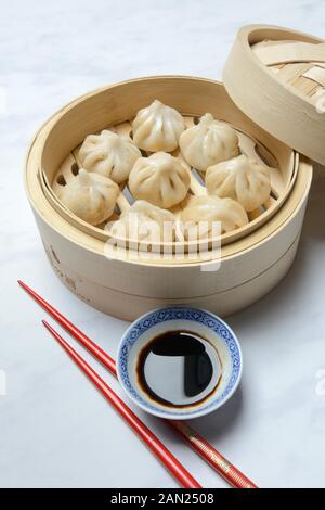 Dim Sum, gefüllte Teigtaschen, gedünstet in Bambuskörben mit Sojasauce und Stäbchen, Deutschland Stockfoto