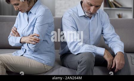 Senior Paar sitzt auf der Couch mit schlechten Nachrichten überwältigt, deprimiert Stockfoto