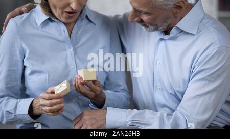 Ältere Dame mit vorhanden, liebevollen Mann sie umarmen, glückliches Paar überrascht Stockfoto