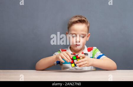 Junge montiert ist eine Rubik's Cube. Konzept der Logik der Entwicklung und Kinder Selbstbewusstsein. Kopieren Platz an der Wand Stockfoto