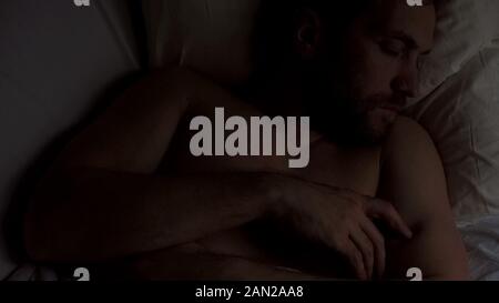 Müde männlichen Erwachsenen schlafen alleine im Bett, Ruhe in der Nacht, Ansicht von oben Stockfoto