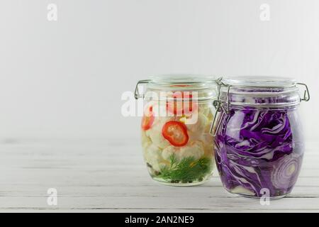 Zwei Gläser von fermentierten roten Kohl, Blumenkohl. Gemüse auf einem hellen Hintergrund. Gärung ist eine Quelle von Probiotika Stockfoto