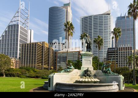 Sydney, Australien - Mai 08 2018: Der alte Gouverneur Phillip Fountain und die Statue im Royal Botanic Garden stehen im Kontrast zu modernen Bürogebäuden in Syd Stockfoto