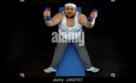 Aktive fat man Hanteln sitzen auf Matten, sport Motivation, Disziplin Stockfoto
