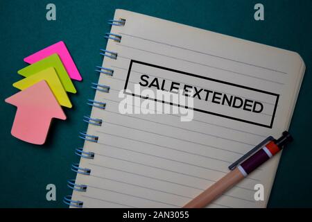 Verkauf erweitert auf ein Buch, das auf grünem Hintergrund schreiben. Stockfoto