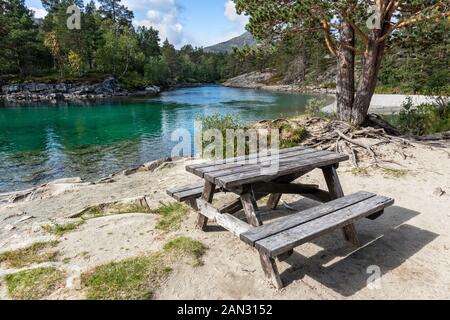 Camping Rastplatz für Picknick mit hölzernen Tisch Bank auf Sand durch den kalten Sekt Fluss in einem Pinienwald Bergen in Norwegen Stockfoto