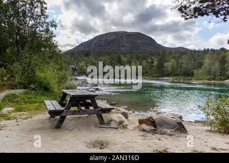 Camping Rastplatz für Picknick mit hölzernen Tisch Bank auf Sand durch den kalten Sekt Fluss in einem Pinienwald Bergen in Norwegen Stockfoto