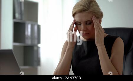 Müde weibliche Chef im Büro sitzen, leiden unter Kopfschmerzen und Verspannungen Stockfoto