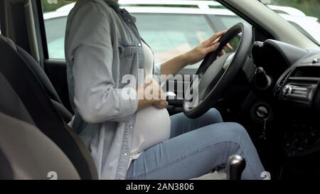 Schwangere Frau im Auto, die Hand auf dem Bauch, active Baby während des dritten Trimesters Stockfoto