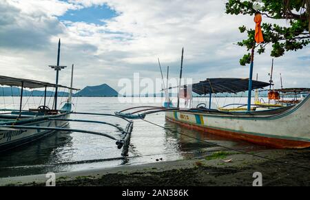 Ausleger am Ufer des Taal See auf den Philippinen mit Blick auf die schlafende Binintiang Malaki (Big Leg) Vulkan. Stockfoto