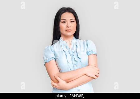 Freestyle. Asiatische Frau stehen auf weißen verschränkte Arme isoliert nachdenklich Stockfoto