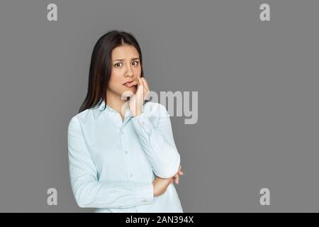 Freestyle. Junge Frau steht auf grauen Beißen Nägel isoliert nervös Stockfoto