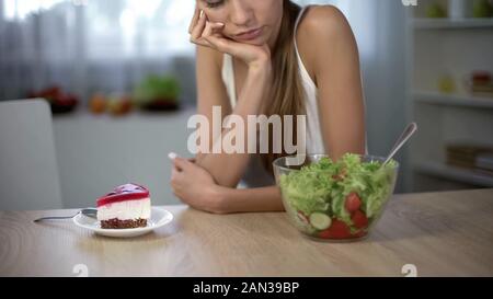 Schlanke Frauen die Wahl zwischen Kuchen und Salat, gesunde Ernährung vs hochkalorische Lebensmittel Stockfoto