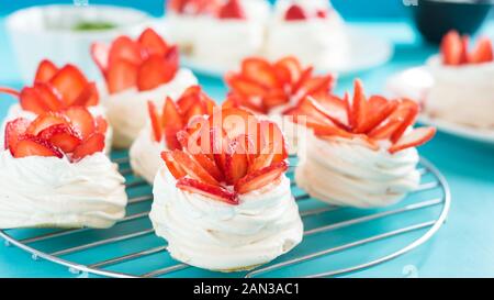 Eine kleine Baiser Pavlova Dessert mit einigen Erdbeere Schichten auf einem blauen Hintergrund. Stockfoto