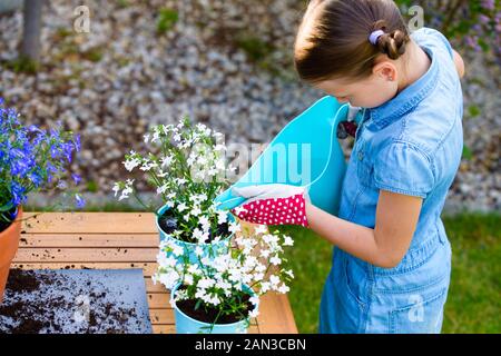 Kleines Mädchen Bewässerung frisch gepflanzten Blumen in Töpfe Stockfoto